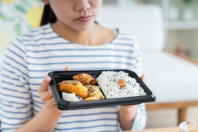 コンビニ弁当をながめる女性