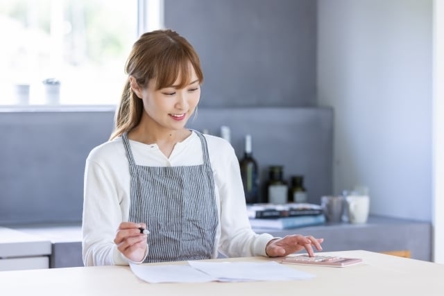 家計簿を眺めて喜ぶ女性