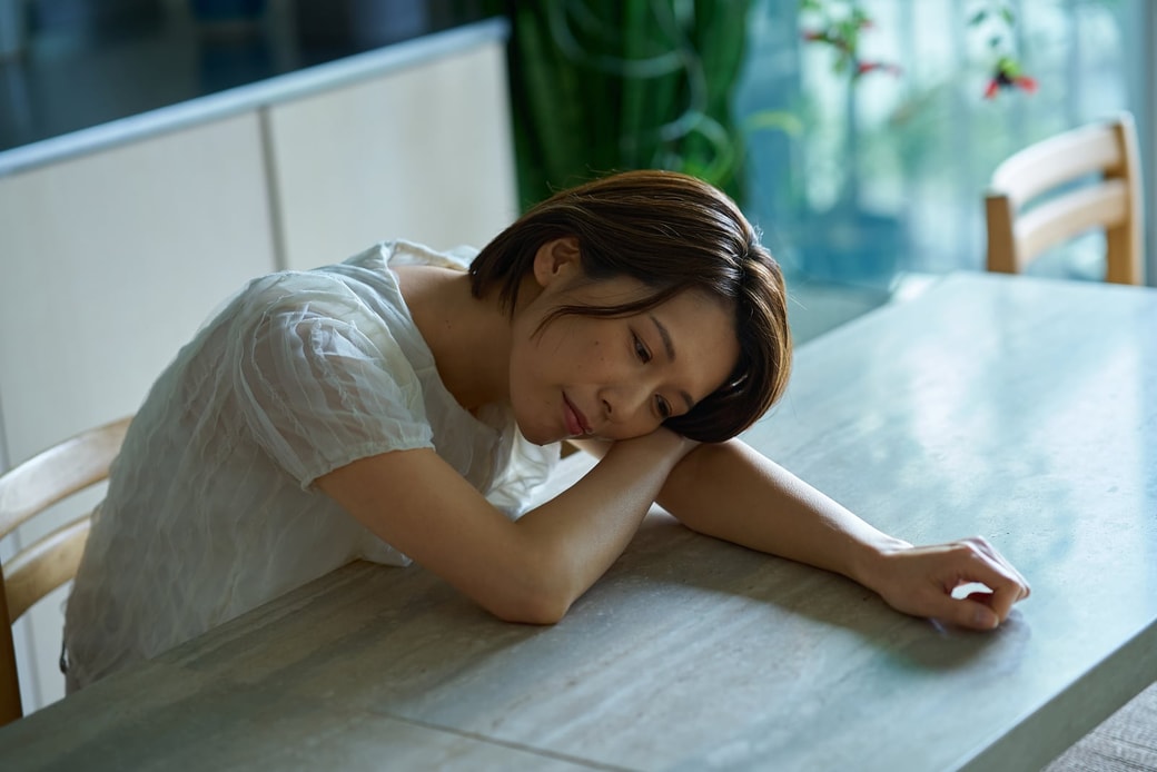 疲れた表情でテーブルに寄りかかる女性
