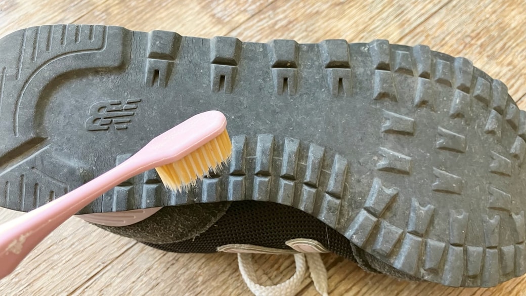 歯ブラシを靴底の溝掃除に使用している様子