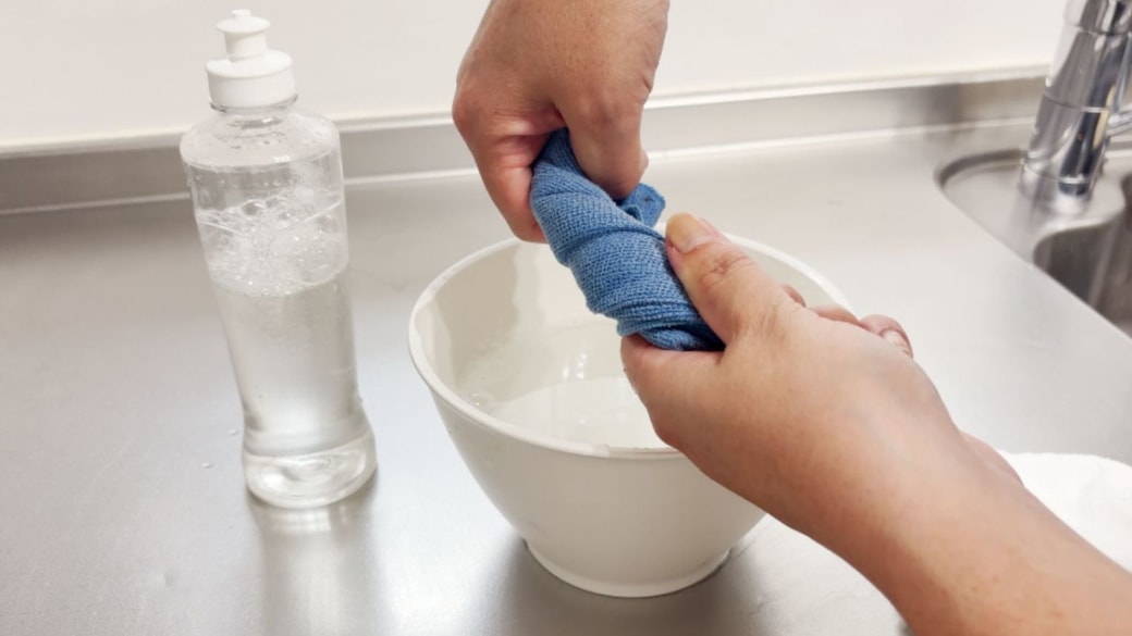 薄めた洗剤液に浸したクロスを絞る