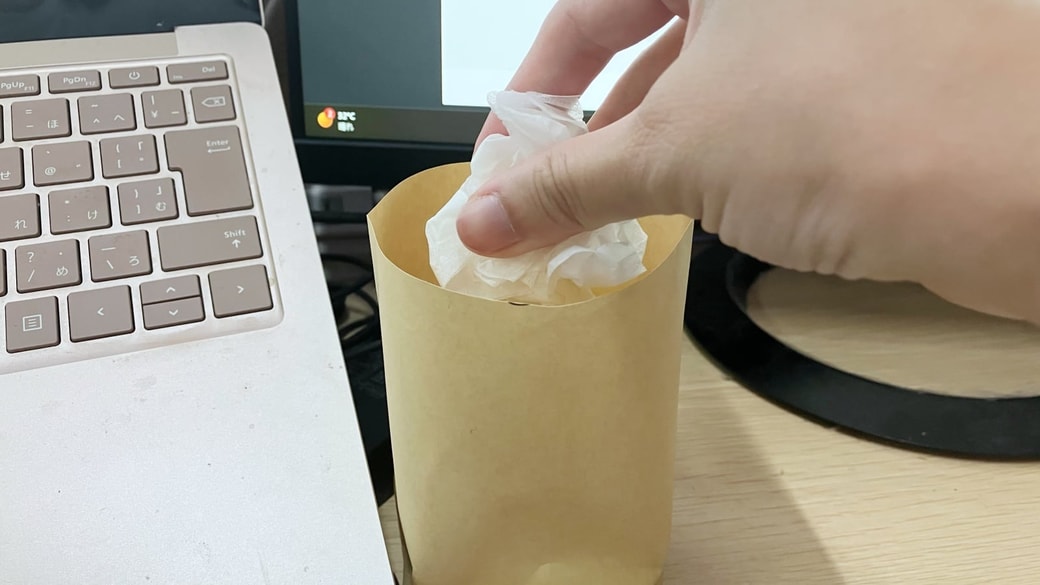 封筒で作った卓上ゴミ箱にゴミを入れている様子