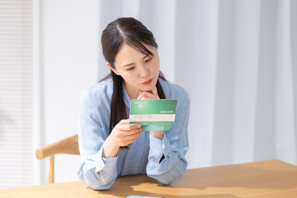 通帳を見て悩む女性