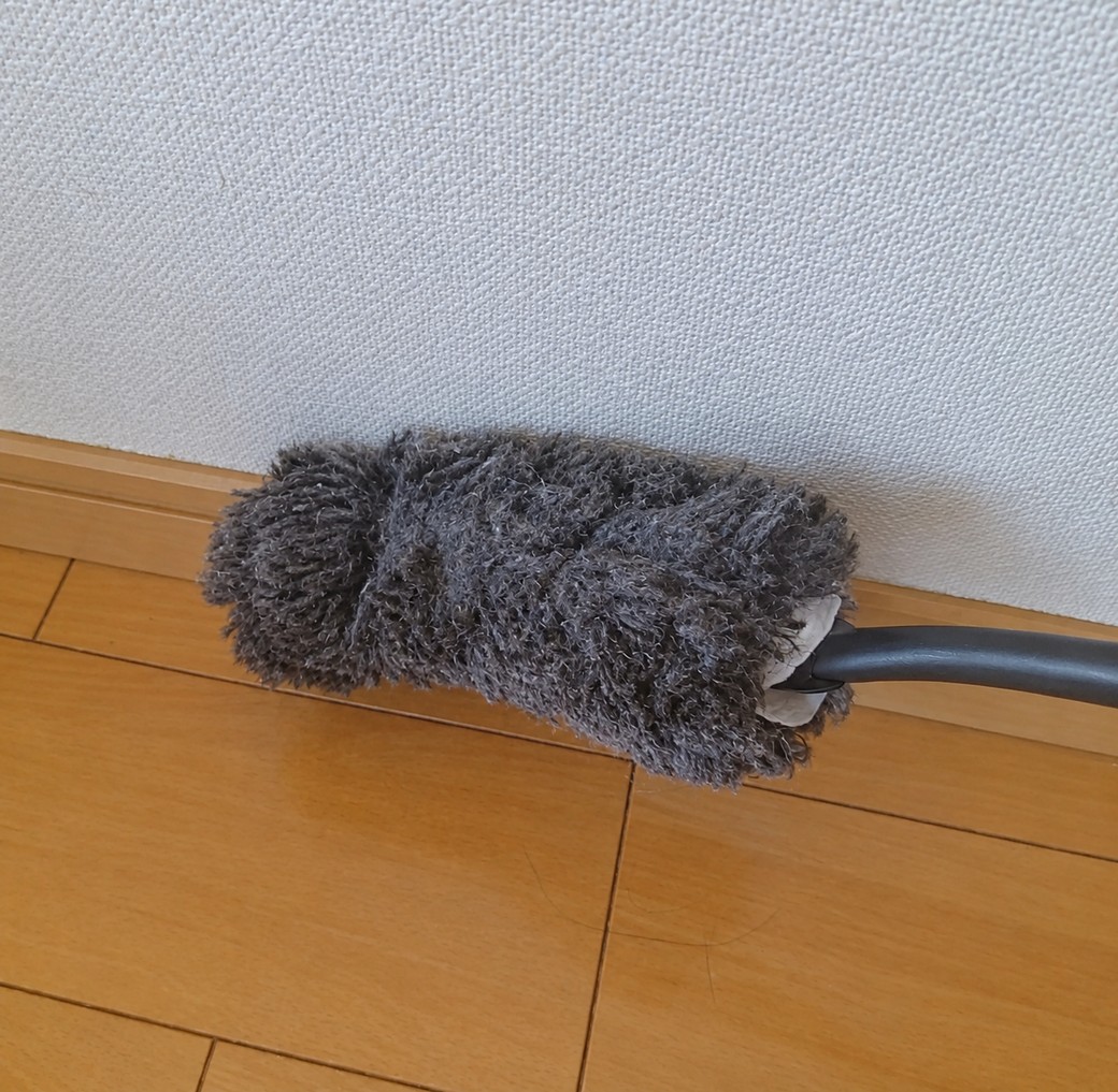 ハンディモップで巾木を掃除する人