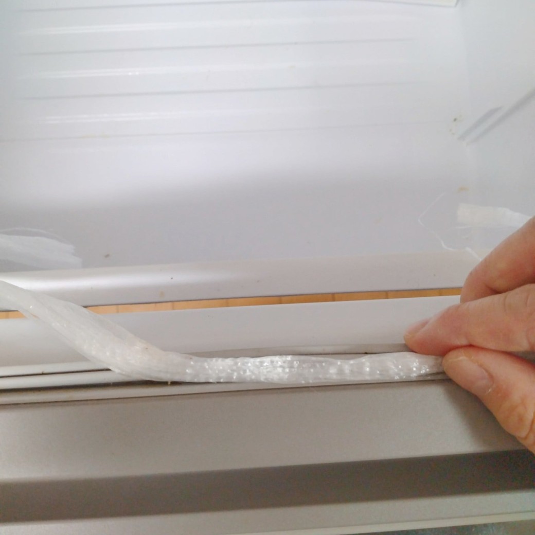 冷蔵庫のすき間を掃除する人