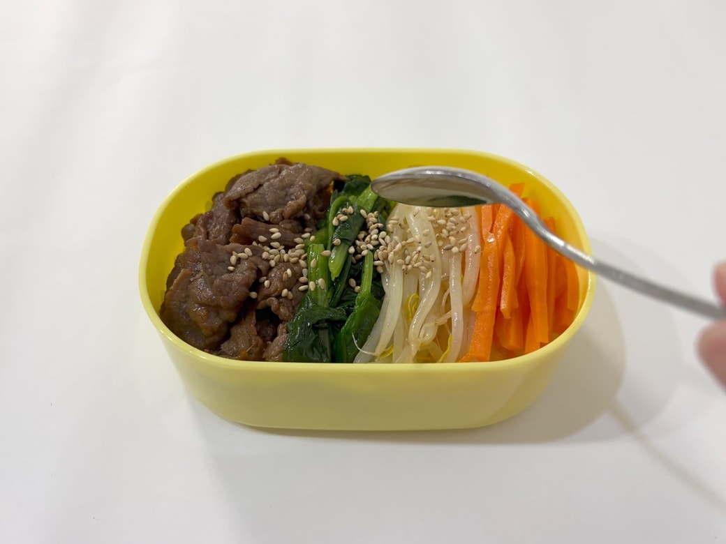 ご飯と具材を詰め、白いりごまを振る