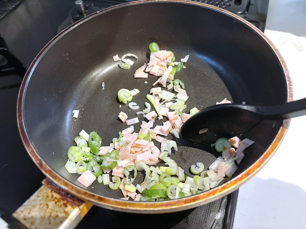 手順1.フライパンにごま油をひいて、刻みねぎと刻んだハムを炒め