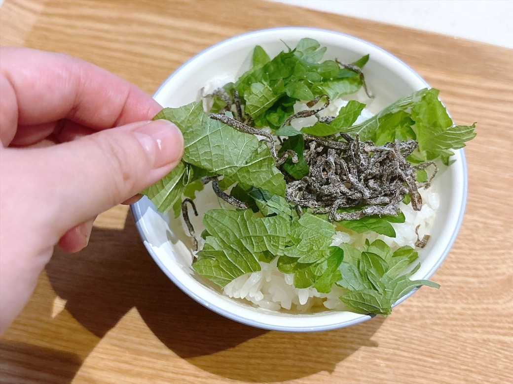 手順1.ごはんを深さのある器に入れ、塩昆布・大葉・ごま油・白ごまを加えて混ぜる