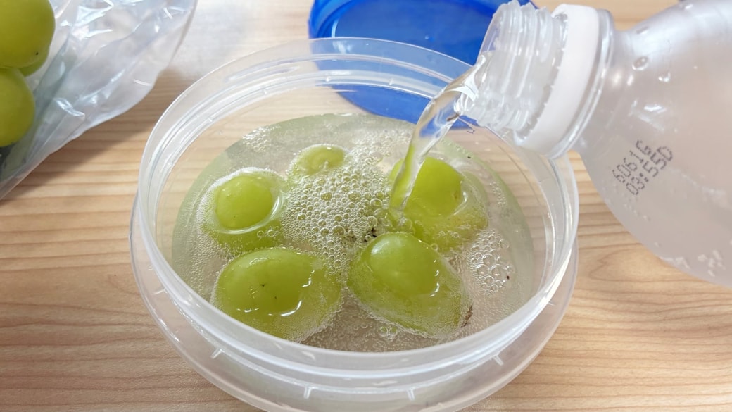 シャインマスカットの入った容器に炭酸水を注いでいる様子