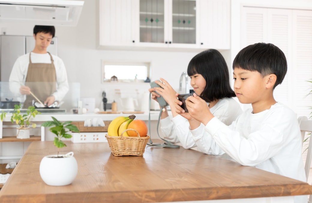 食卓でスマホを見る子どもたち