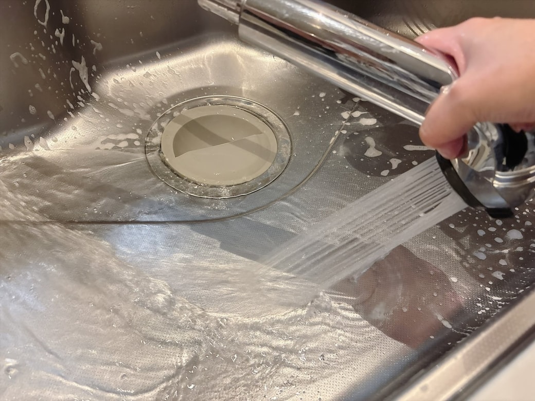 キッチンシンクに水をかけて洗い流す