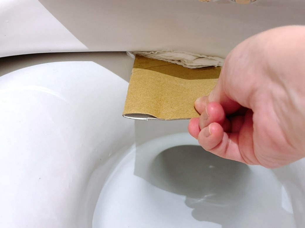 手順3.便器のふちにトイレットペーパーの芯を押し込んで、手前に引く