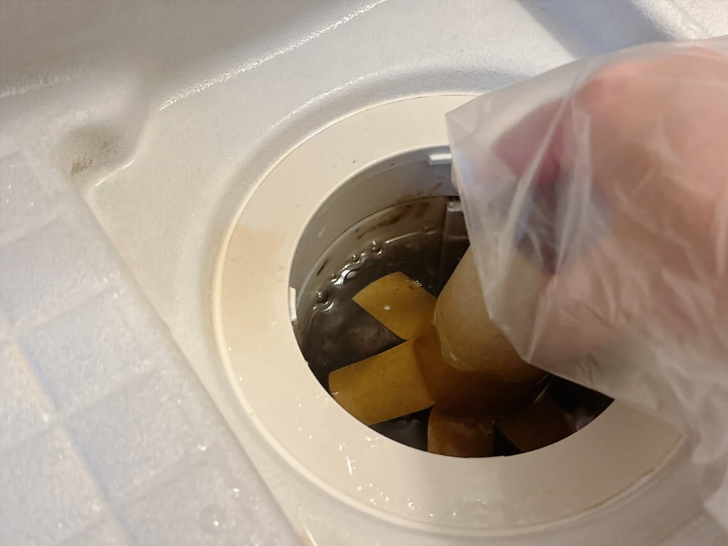 手順2.手にポリ袋をはめて、浴室の排水口にさきほど切り込みを入れたトイレットペーパーの芯を差し込み、ゆっくりまわす