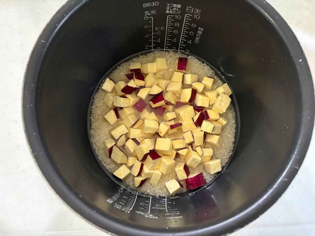 炊飯器に米、調味料、水、さつまいもを入れて炊飯する
