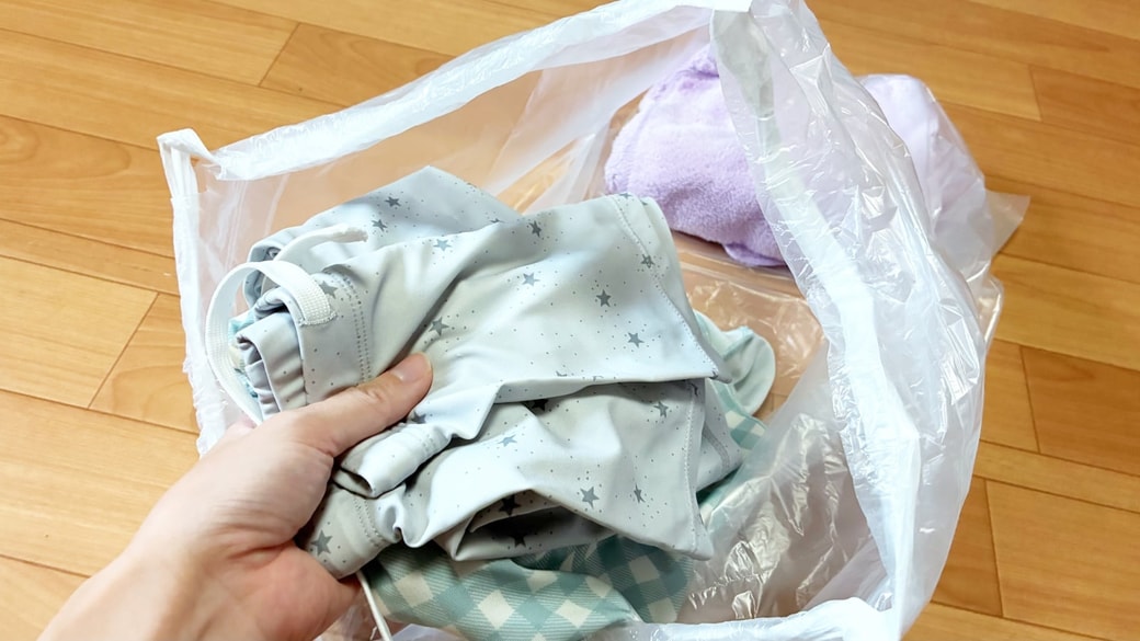 3COINSのひもつきロール式ゴミ袋に濡れたタオルや着替えを入れている様子