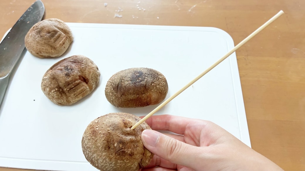 竹串にしいたけを刺している様子
